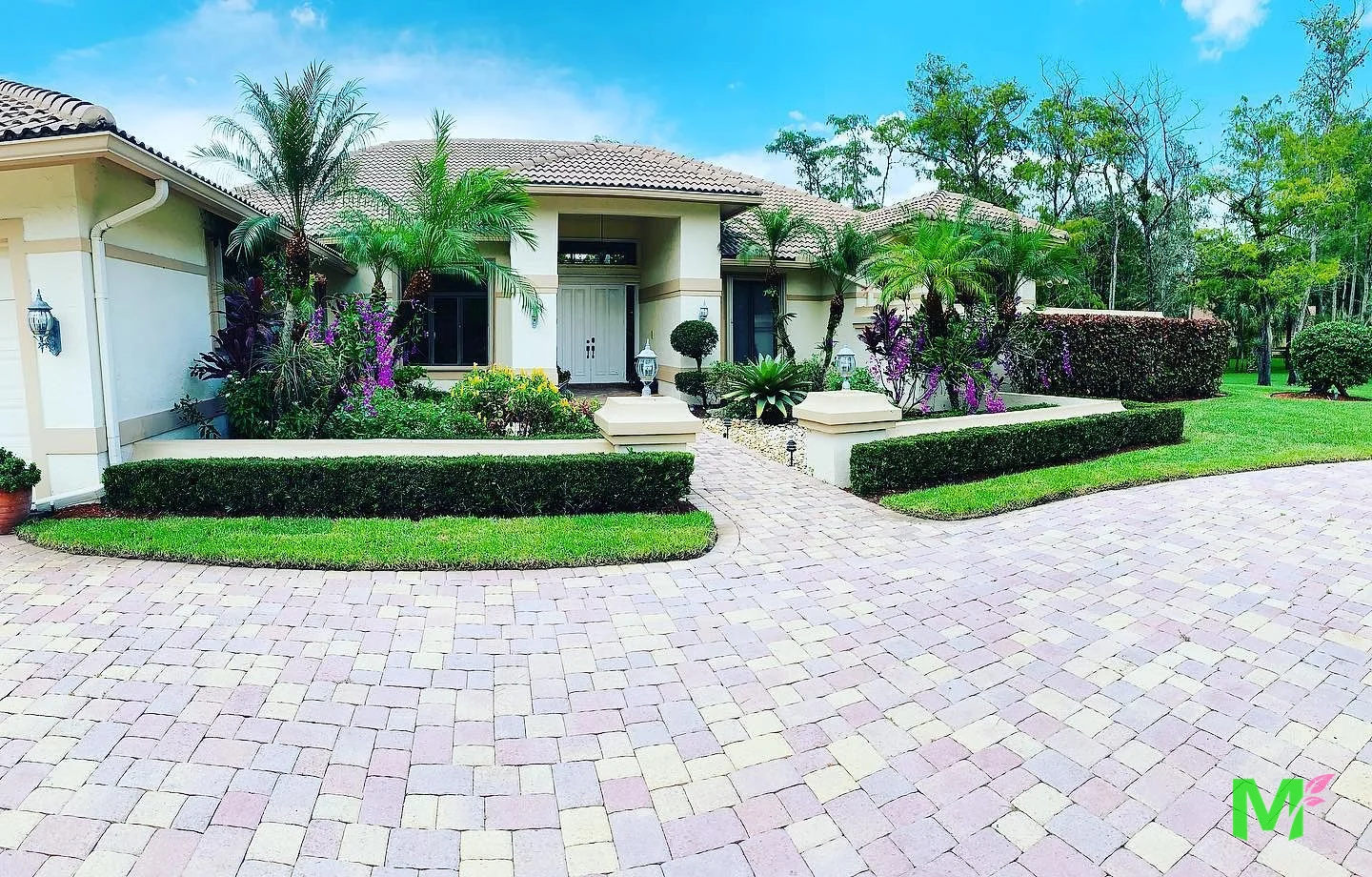 Estate front elevation with layered tropical planting, clipped hedges and a paver walkway to the entry