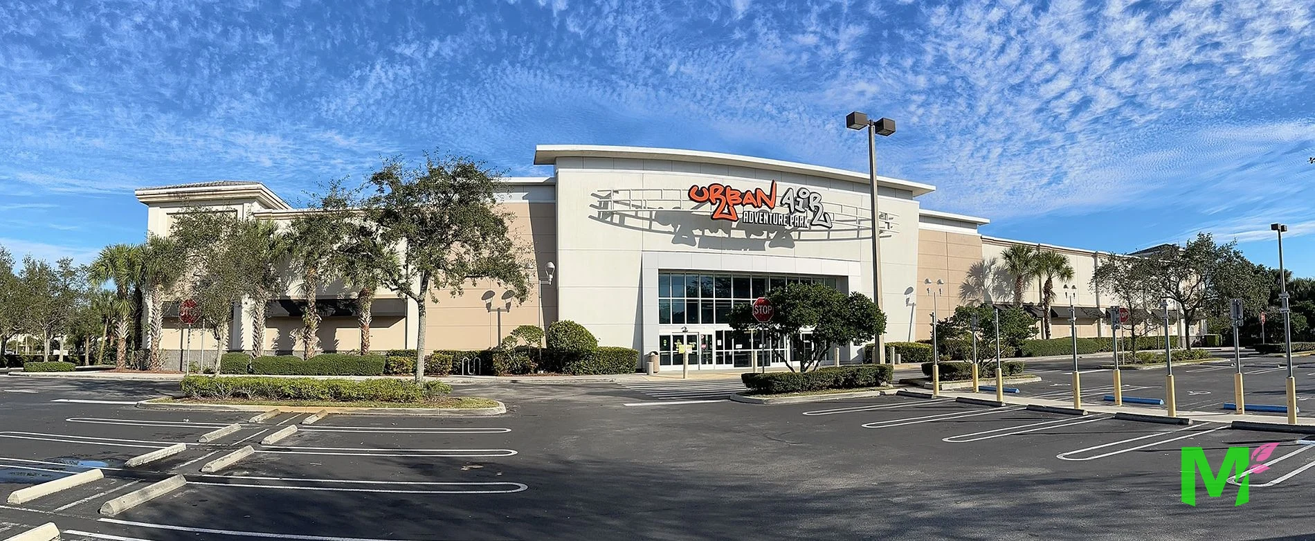 Retail entertainment plaza with maintained hedge rows, palms and shade trees along the parking field
